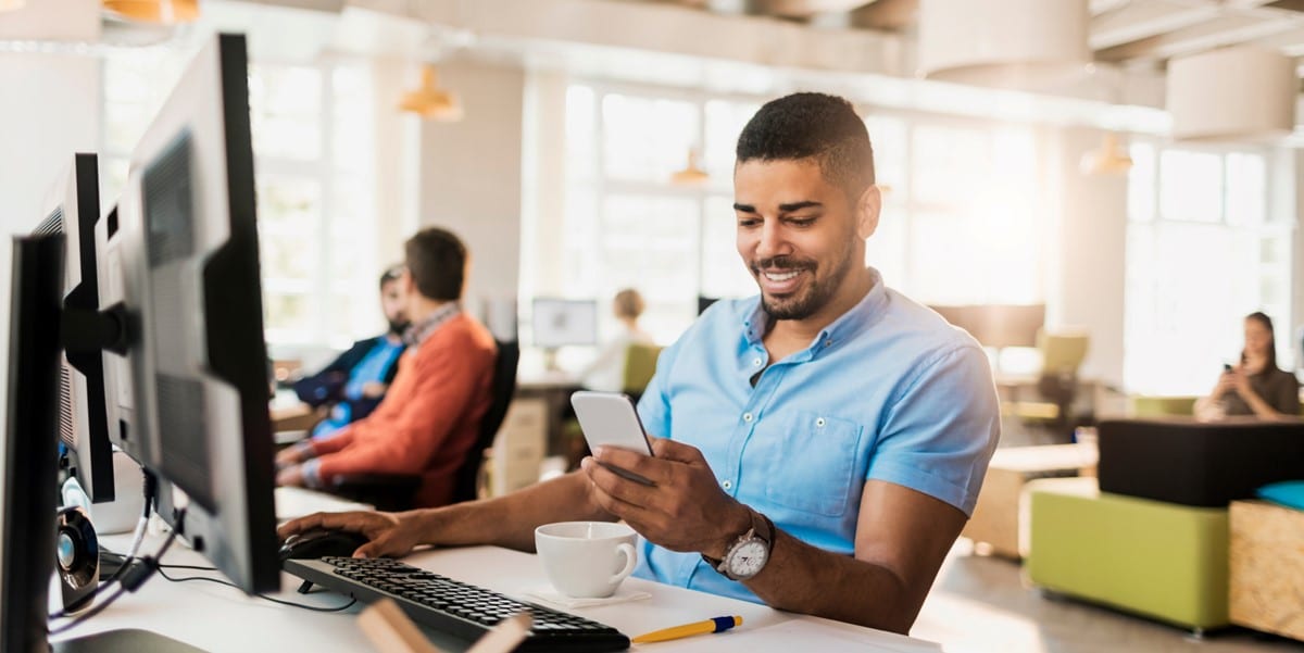 professional working in office, looking at cellphone, sitting at work desk