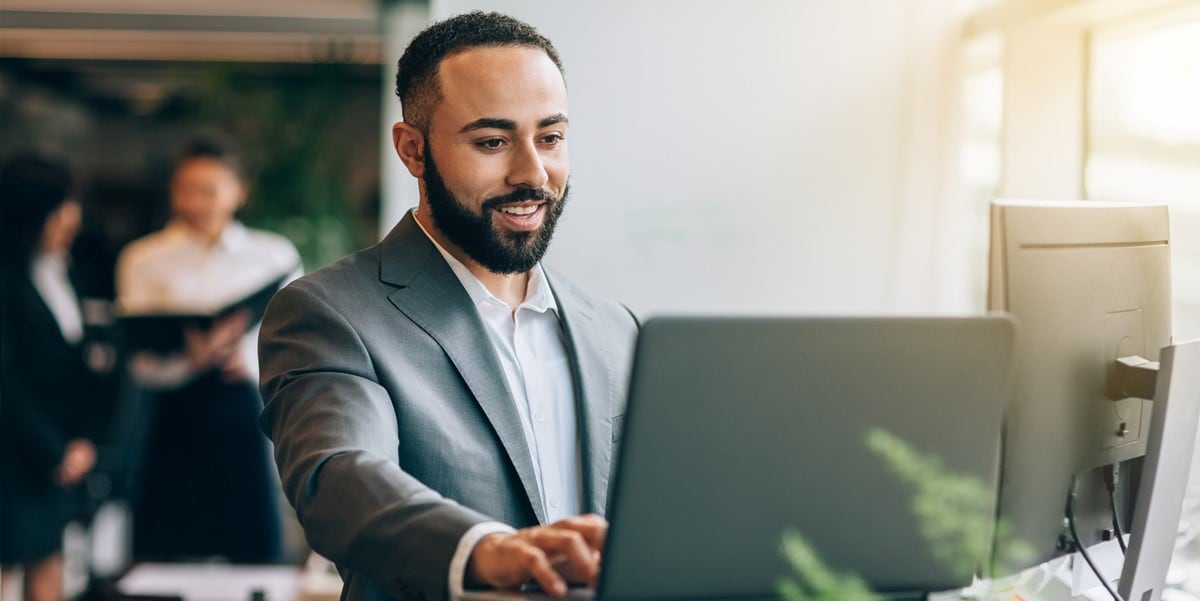 man in grey suit working at computer, office setting